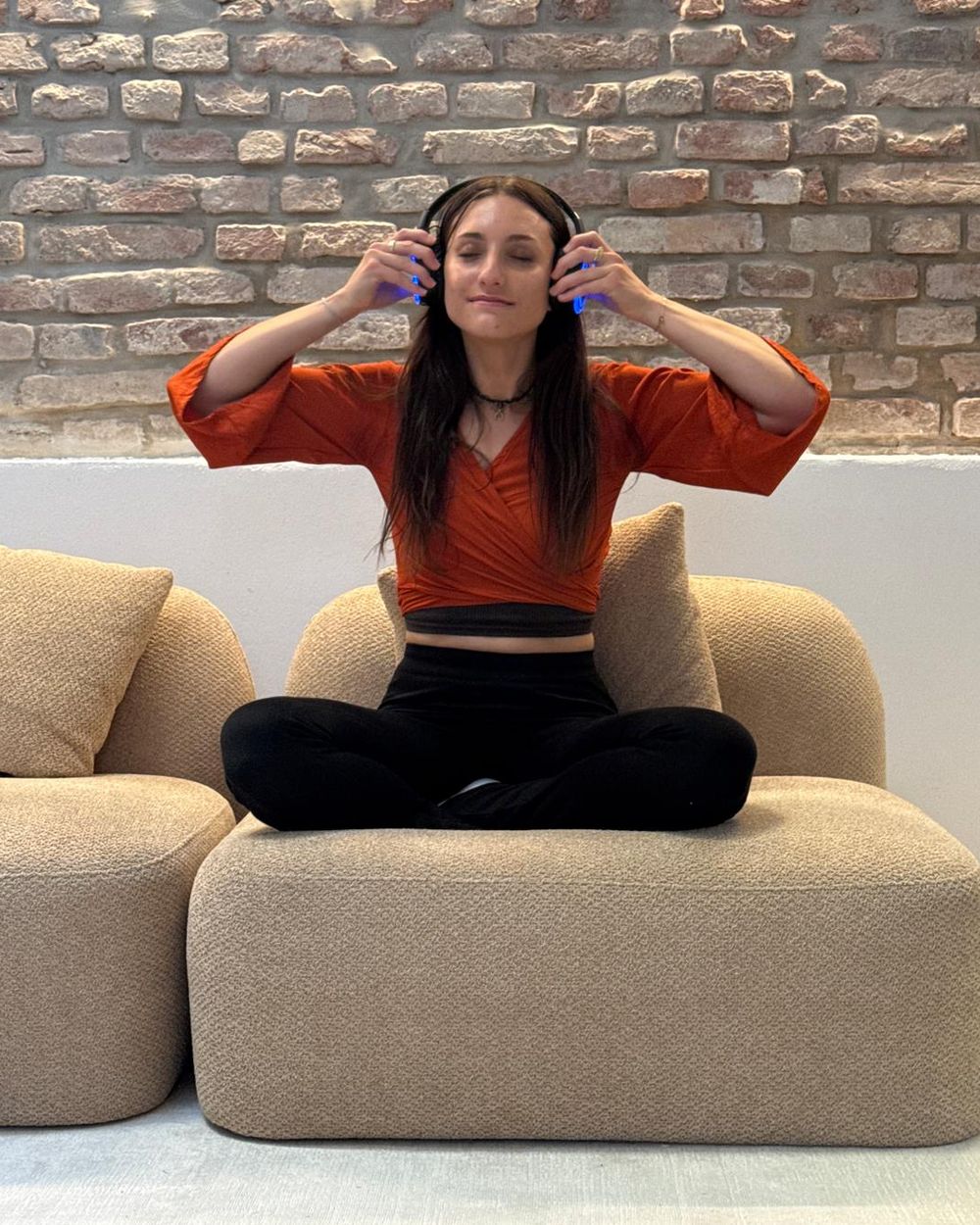 Nina sitzt mit geschlossenen Augen und Kopfhörern auf einem Sofa