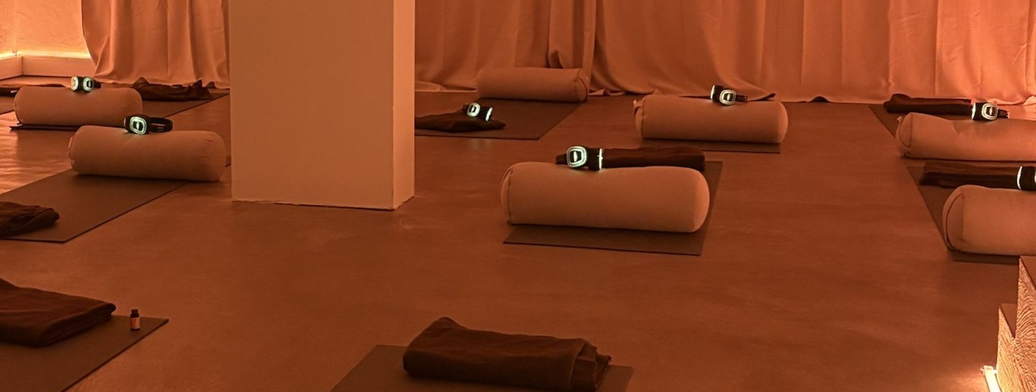 Abgedunkelter Raum mit Matten, Bolsters und Kopfhörern für eine Breathwork-Gruppe